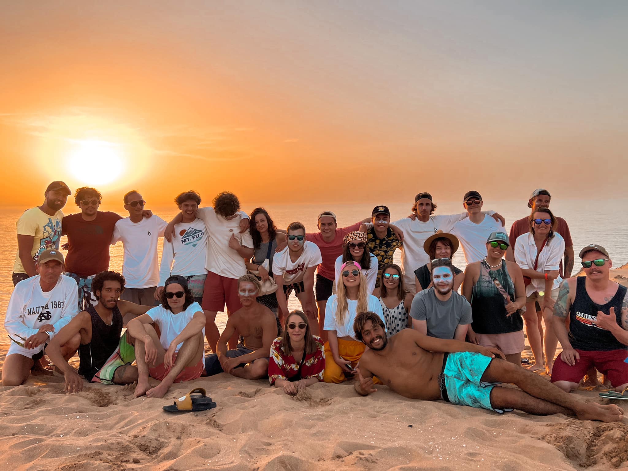 Camp guests and coaches together on the beach at sunset