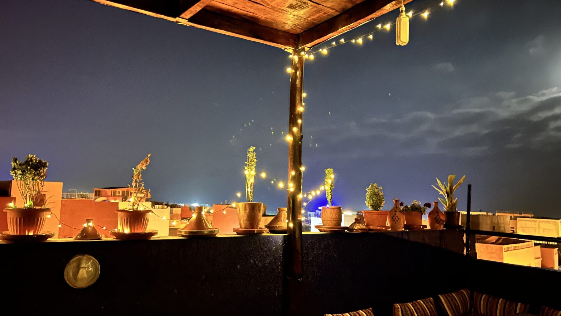 Riad rooftop at dusk, strung with lights