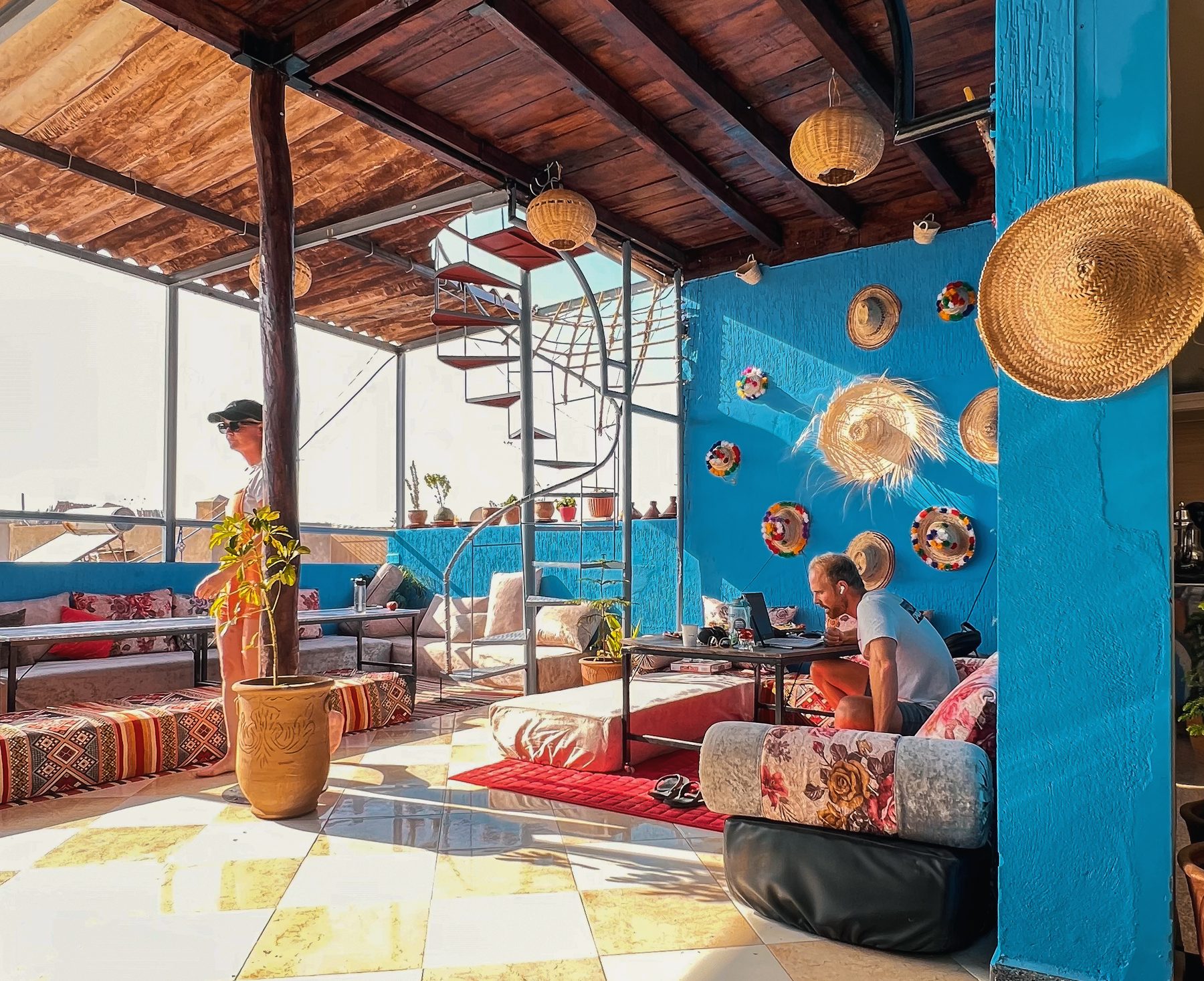 Covered rooftop terrace of the riad with Berber seating and a blue Moroccan wall