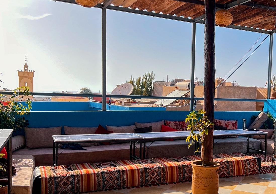 Covered rooftop terrace with long benches, looking over Tamraght