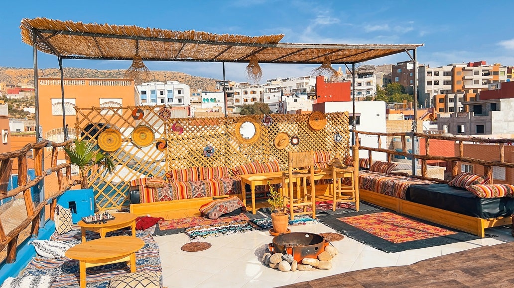 Shaded rooftop terrace of the riad with Berber seating, above the village