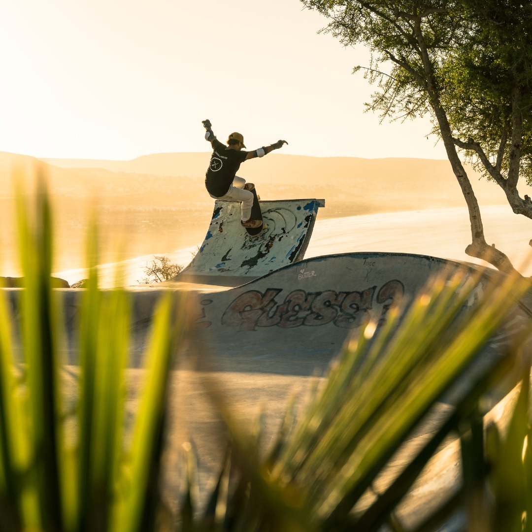 Skater carving a concrete bowl at golden hour